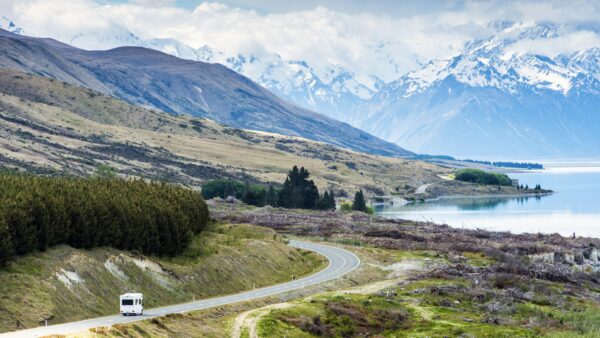 RV driving near mountains and lake in remote landscape